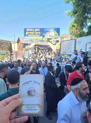 Un pèlerin tenant le livre du Tikoun Haklali devant l'entrée du Tsioun